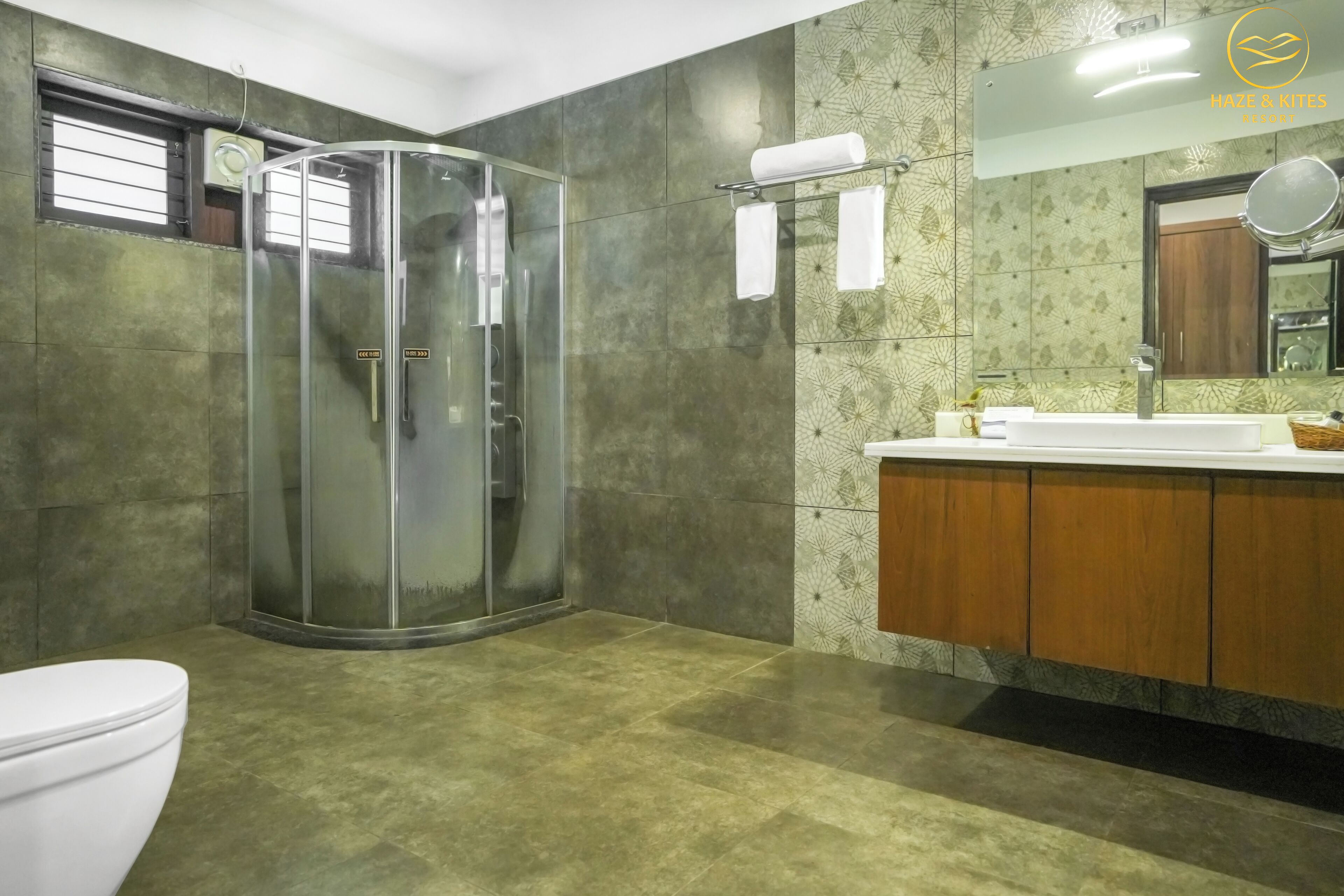A modern bathroom with a glass-enclosed shower, a white toilet, and a vanity with a mirror.