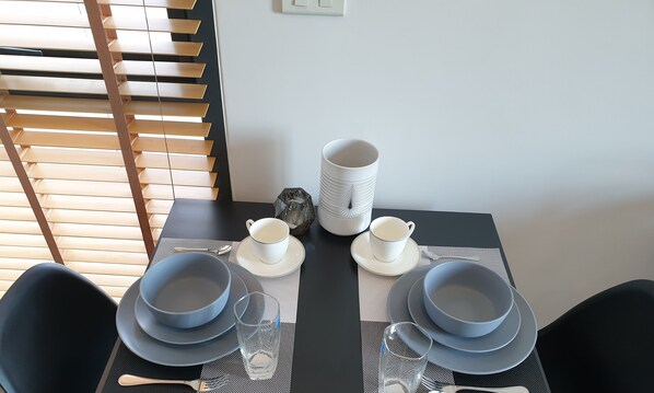A dining table set with blue plates, white cups, and a decorative vase.