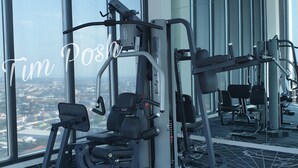 Ett gym med olika typer av träningsredskap, stora fönster och ett mönstrat golv.