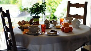 Une table de petit-déjeuner avec divers aliments, une plante en pot et une vue sur la verdure à l’extérieur.