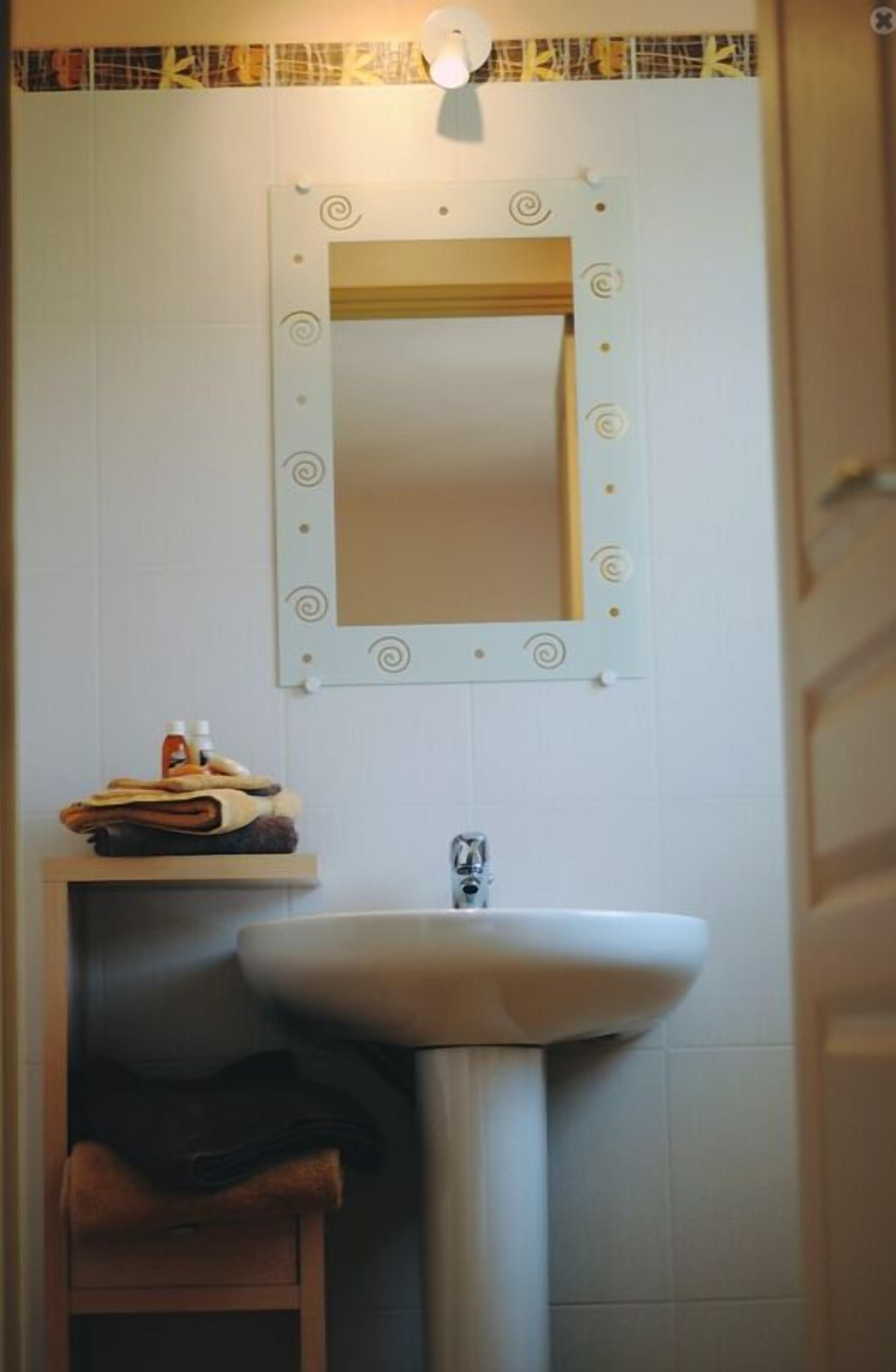 Un baño con lavamanos, espejo y perchero para toallas.