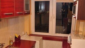 Cozinha compacta com fogão a gás, pia e janela com vista para o exterior.