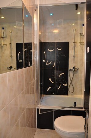 Un baño moderno con ducha envuelta en vidrio, bañera y retrete.
