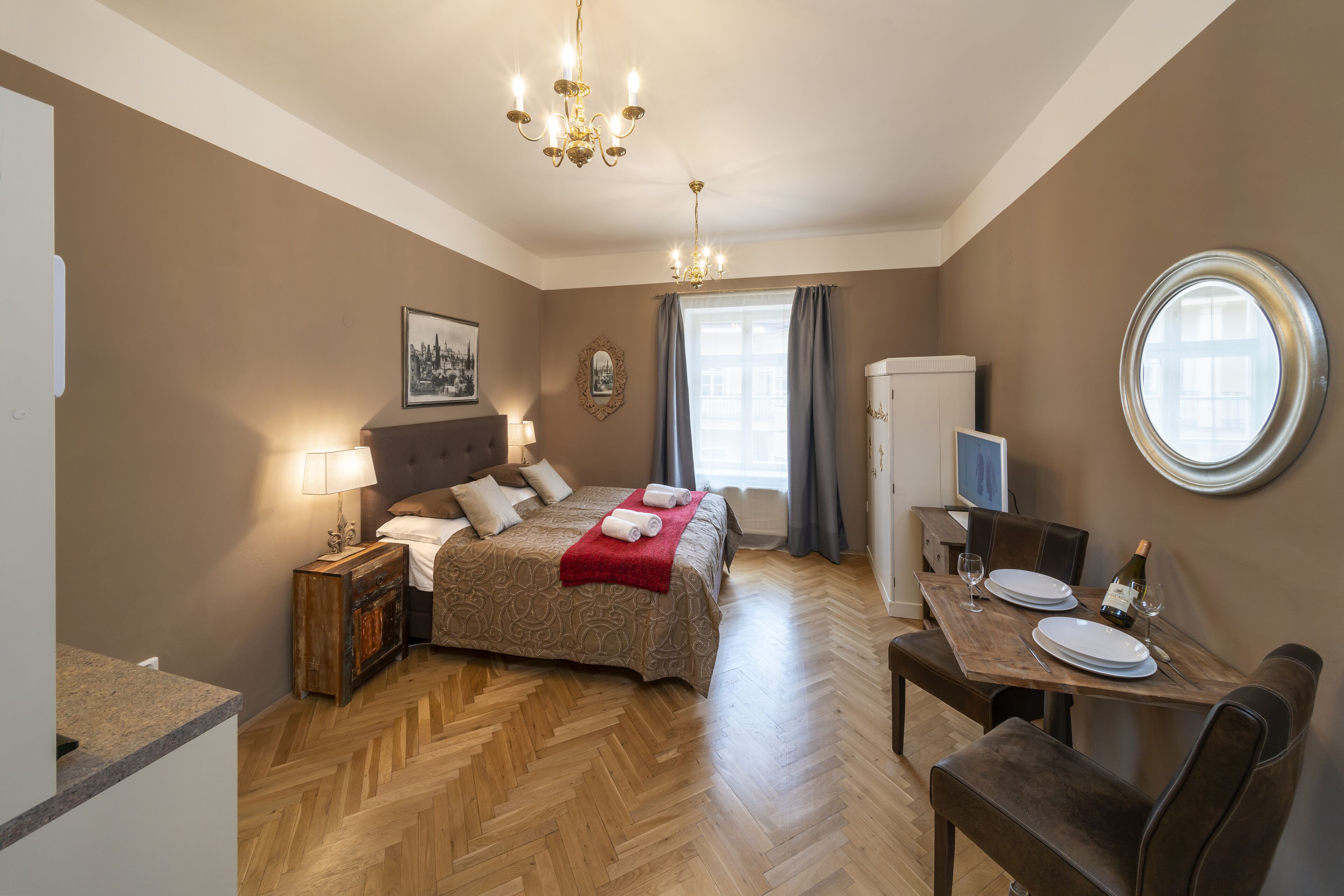 Un dormitorio con cama, mesita de noche, lámpara y un rincón comedor con una mesa para dos personas.