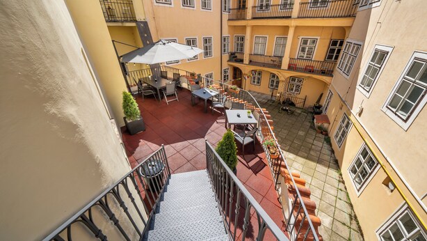 Ein mehrgeschossiges Gebäude mit Innenhof, der Sitzgelegenheiten im Freien, eine Treppe und Balkone bietet.