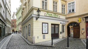 Eine Kopfsteinpflasterstraße mit einem Gebäude, auf dem „Farm Shop Frische Lebensmittel“ steht.