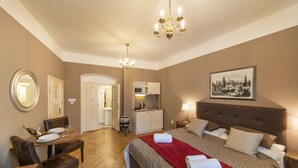 Ein Hotelzimmer mit Bett, Esstisch mit Stühlen, einer Küchenzeile und einem Flur.