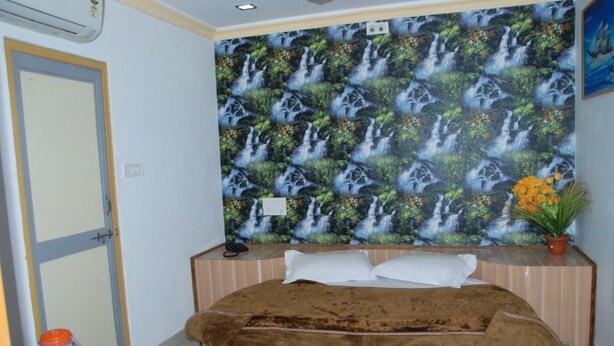 Un dormitorio con una cama grande, una mesita de noche, un teléfono en la pared y una planta en maceta.