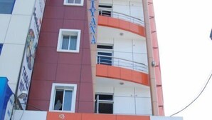 Un hotel de varios pisos con fachada roja y blanca, balcones y entrada al nivel de la calle.