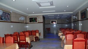 Un restaurante con varias mesas y sillas, iluminación empotrada y televisores montados en la pared.