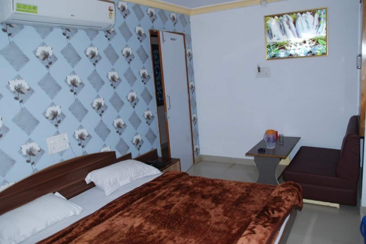 A bedroom with a bed, a small table with a cup, and a sofa.