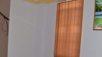 A bedroom with a bed, a ceiling fan, a window with blinds, and a painting on the wall.