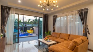 Ein modernes Wohnzimmer mit einer Couch, einem Couchtisch und Blick auf einen Swimmingpool und Außenbereich.