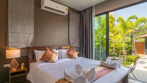 Ein Hotelzimmer mit einem großen Bett, einem Nachttisch, einer Klimaanlage und Blick ins Freie.