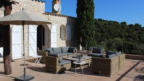 Une terrasse extérieure aménagée avec des meubles en osier, une table et un grand parasol.