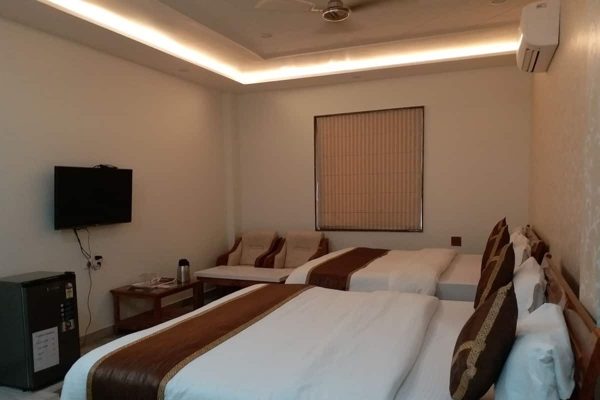 Une chambre d’hôtel avec deux lits, une télévision, un bureau et une fenêtre avec des stores.