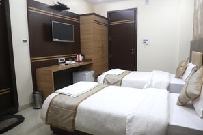 A hotel room with two beds, a desk, a TV, and a wardrobe. - Vandana Residency (Varanasi)