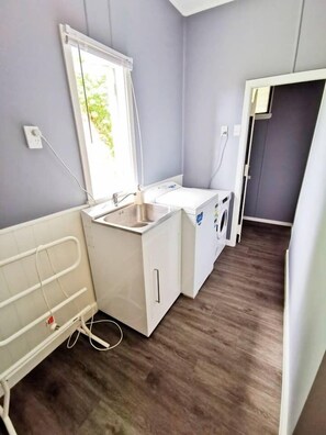A small, modern bathroom with a sink, a mirror, and a window. - 180 Degrees sea view house (Oamaru)