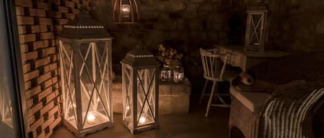 A cozy room with a brick wall, wicker furniture, and lit lanterns.