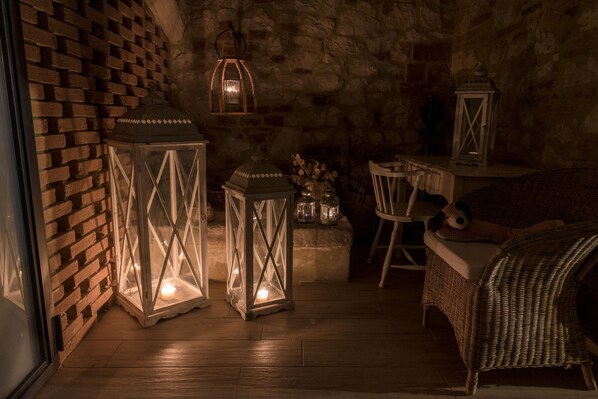 A cozy room with a brick wall, wicker furniture, and lit lanterns.