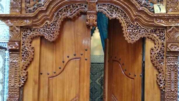 A wooden door with intricate carvings and a decorative ceiling light. - Riad Bab Berdaine (Meknes)