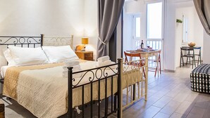 A bedroom with a bed, bedside table, lamp, and a view of the balcony. - Santa Croce Apartment (Florence)