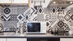 A kitchen with a microwave, a sink, and a stainless steel kettle. - Santa Croce Apartment (Florence)