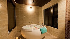 Une salle de bain moderne avec une baignoire sur pieds, un grand miroir et un sol carrelé.