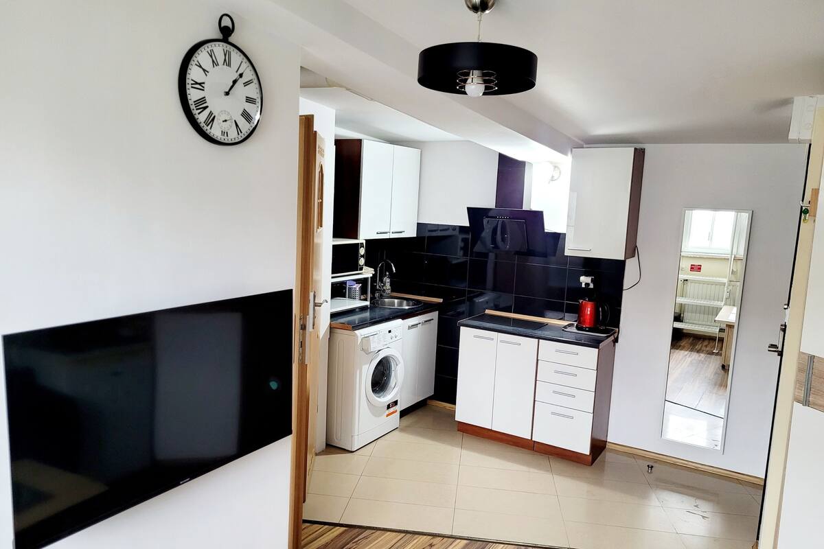Una cocina moderna con lavadora, encimera negra y un reloj en la pared.