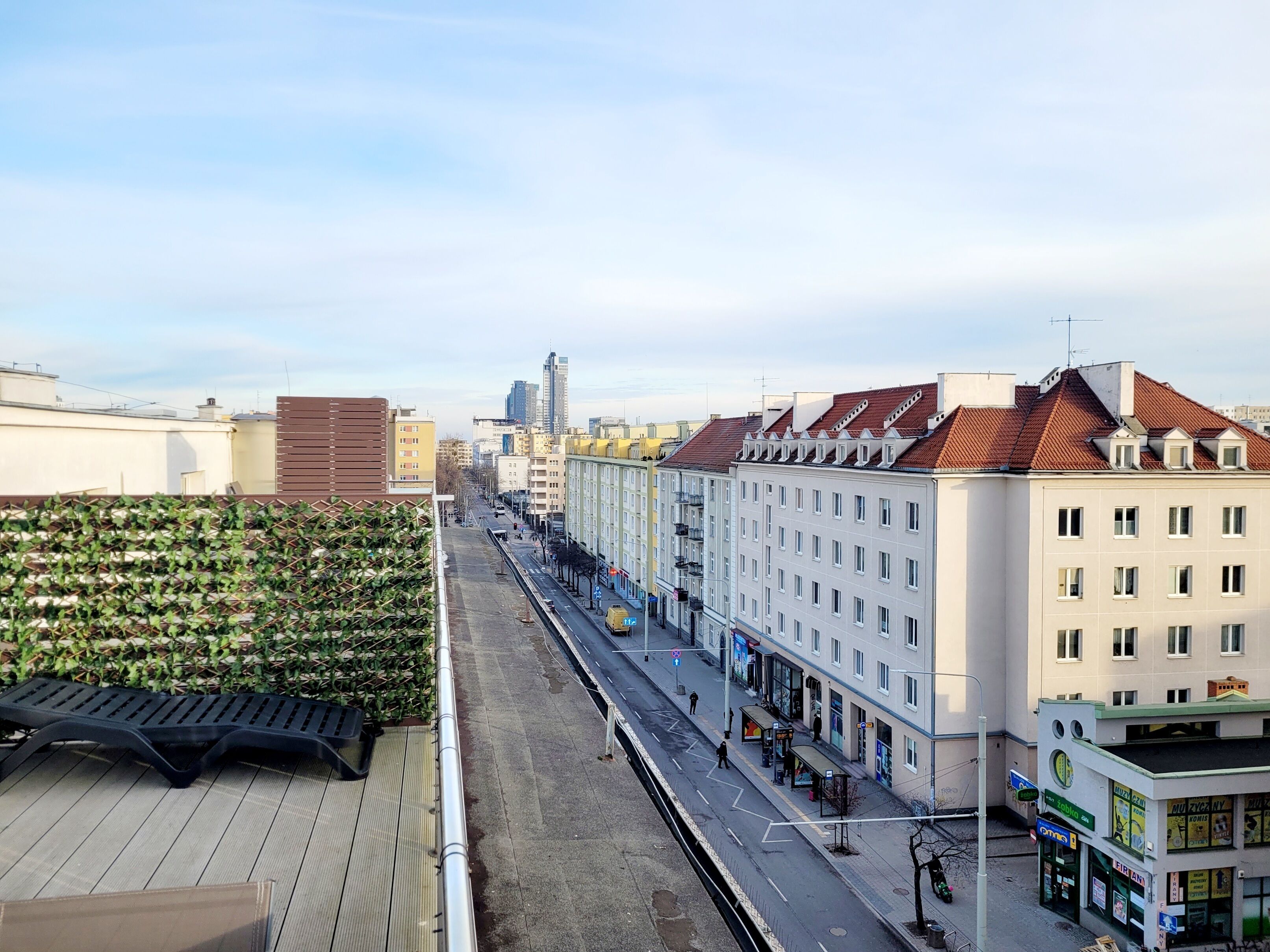 A city street with buildings, a tram, and a pedestrian walkway.