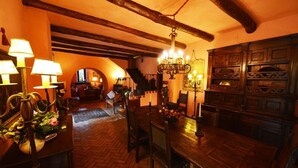A warmly lit dining area with wooden furniture, a chandelier, and a herringbone-patterned floor. - Relais La Torricella - Villa in the Sorrento Peninsula (Vico Equense)