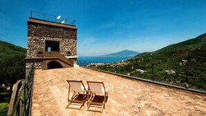 A stone building with a terrace and two lounge chairs. - Relais La Torricella - Villa in the Sorrento Peninsula (Vico Equense)