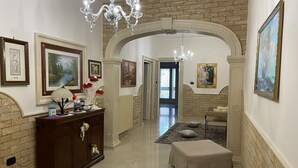 A hallway with a brick wall, a chandelier, a wooden cabinet, and a bench. - Holiday House '' Lu Barocco '' (San Pancrazio Salentino)