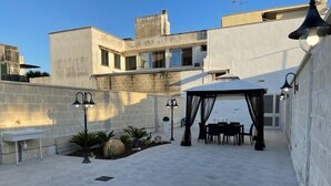 An outdoor patio area with a covered seating area, stone walls, and outdoor lighting fixtures. - Holiday House '' Lu Barocco '' (San Pancrazio Salentino)