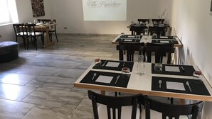 A dining area with multiple tables set for a meal, each with black placemats, cutlery, and glassware.