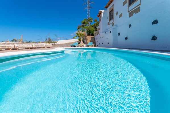 Ein klares, blaues Schwimmbecken mit einem weißen Gebäude im Hintergrund.