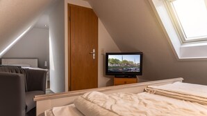 A bedroom with a bed, a television, a wardrobe, and a skylight.