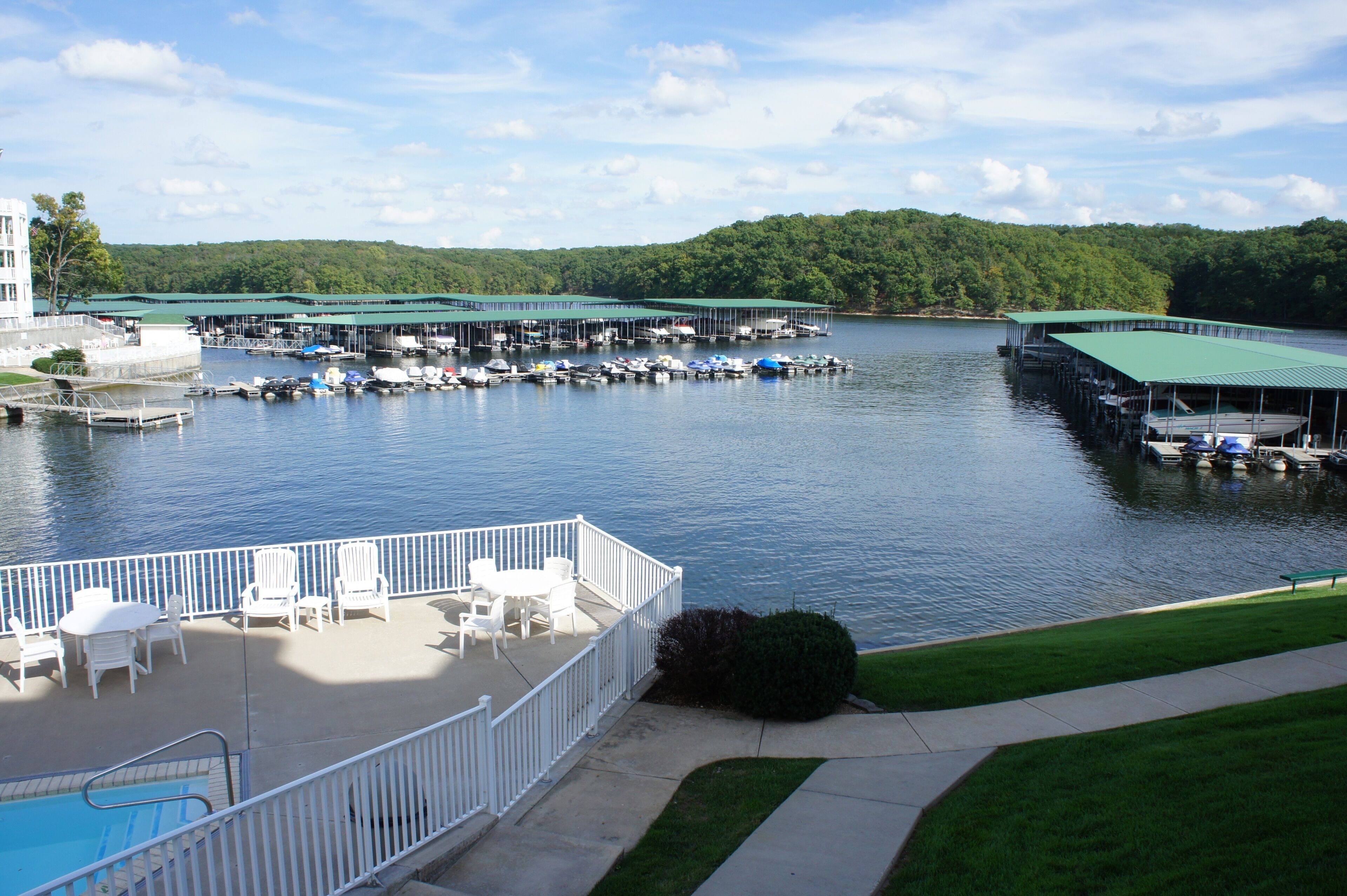 A marina with boats docked, a covered deck area with chairs and tables, and a swimming pool.