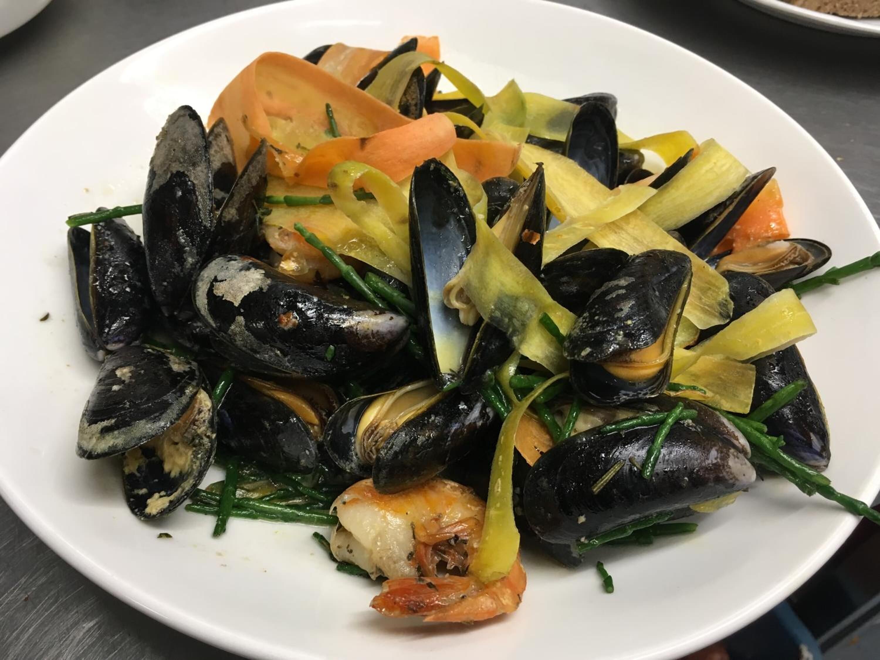 A plate of mussels with vegetables.