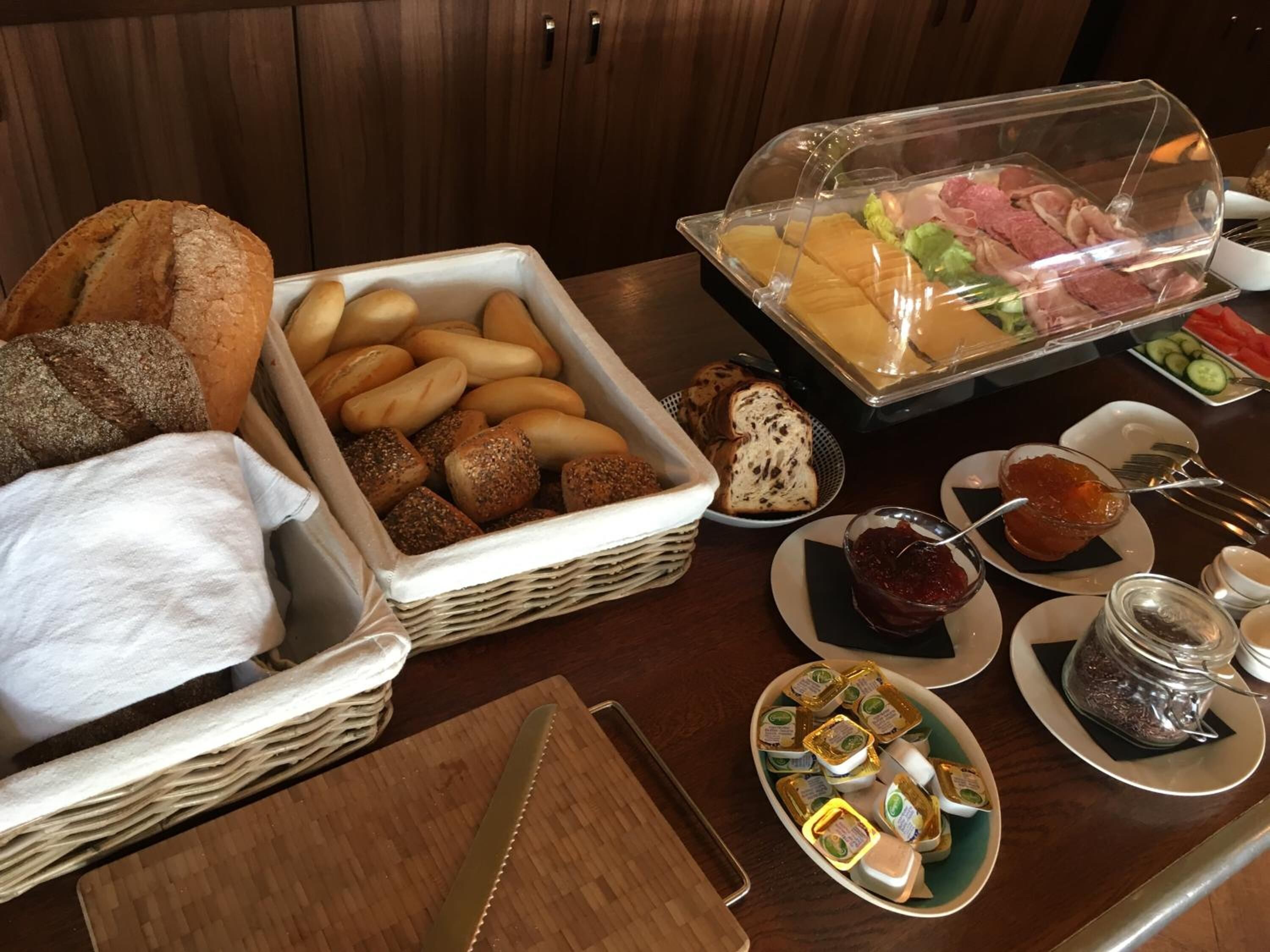 Un bufé con panes, bollería, carnes y salsas variadas.