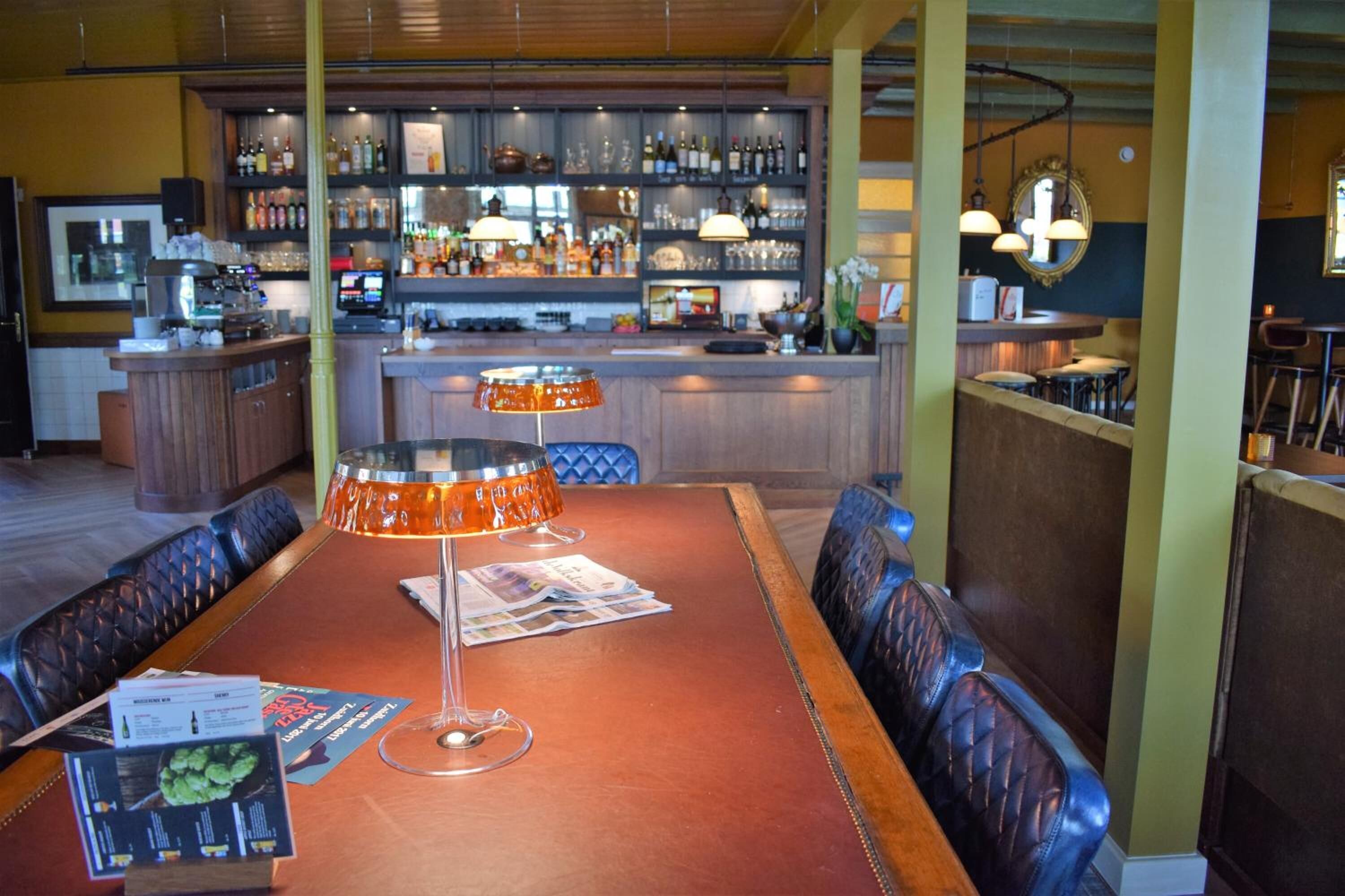 A restaurant with a bar area, wooden tables, and leather booths.