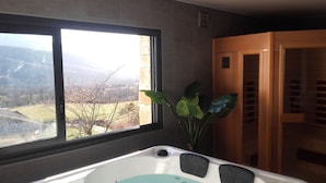 A bathroom with a bathtub, a window with a view of a landscape, and a wooden door. - Superb entirely new housing (Leychert)