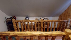 Un lit superposé en bois avec une tête de lit, une petite table avec une bouilloire et un panneau d’accueil.