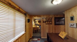 A wooden interior with a dining area, a table with a placemat, and framed pictures on the wall.
