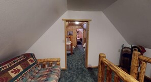 Una habitación con un banco de madera, piso alfombrado y una puerta que da a otra estancia.