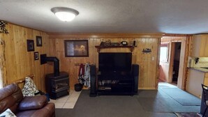 Un intérieur en bois avec une cheminée, un téléviseur et un canapé.