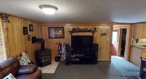 Un interior de madera con chimenea, televisor y sofá.