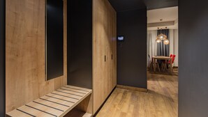 A modern interior with a wooden bench, a dark wall, and a dining area with a table and chairs.