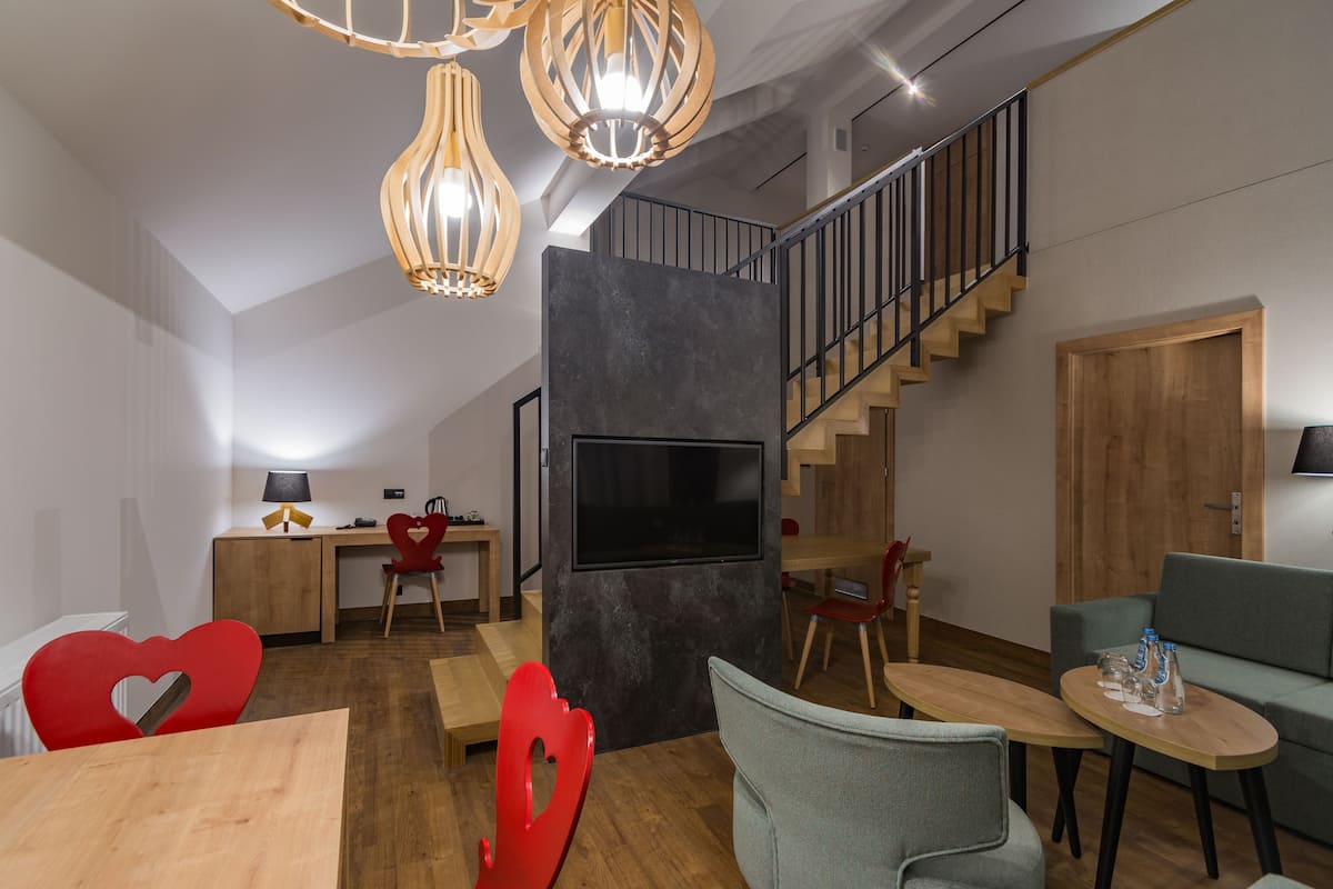 A modern living room with a staircase, a TV, and a dining area with heart-shaped chairs.