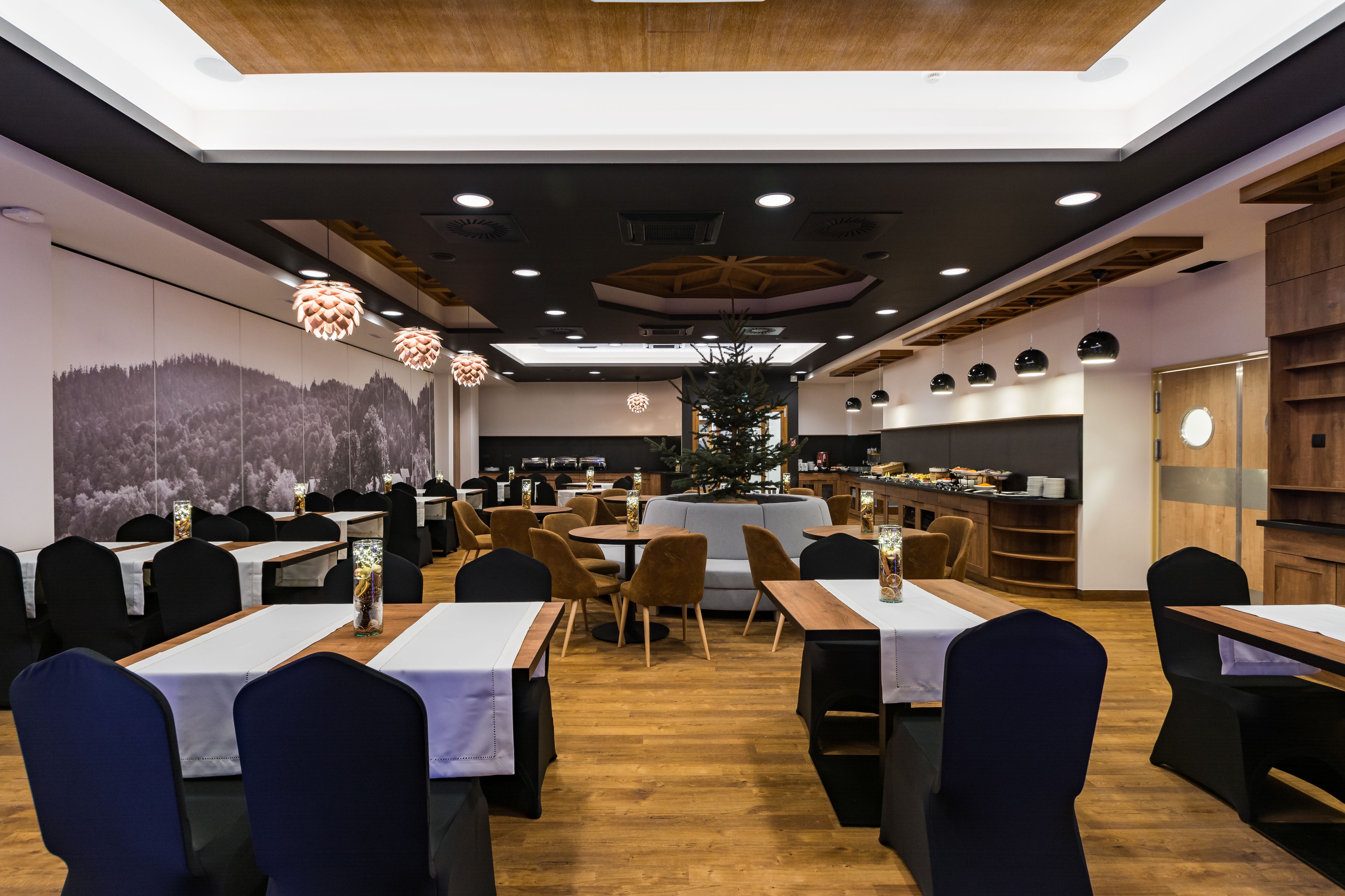 A restaurant with multiple tables and chairs, a bar area, and a large mural on the wall.